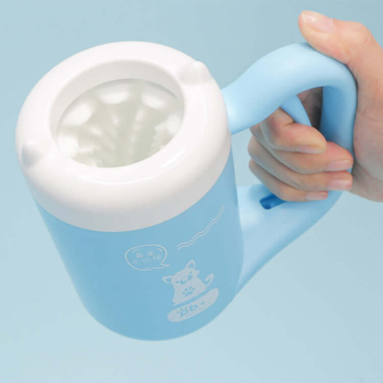 Blue Pet Paw Cleaner Cup with white interior held by a hand against a light blue background