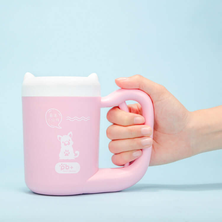 Pink Pet Paw Cleaner Cup with cartoon design held by a hand against a light blue background