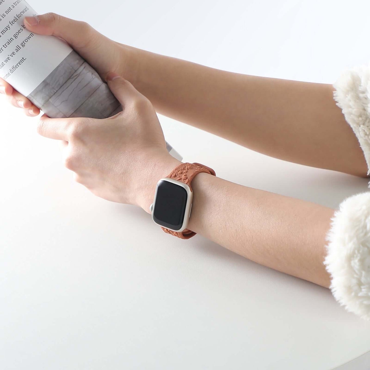 Apple Watch Band – Floral Silicone Strap for Women worn on a wrist holding a magazine